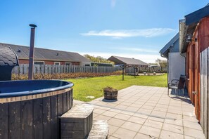 Ein Garten mit Whirlpool, Holzterrasse, Backsteinmauer und umzäunter Fläche.