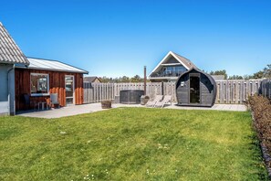 A backyard with a wooden deck, a barbecue area, and a small building with a sloped roof. - 14-person holiday home in Agger with wilderness bath and outdoor sauna (Vestervig)