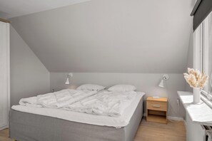 Ein Schlafzimmer mit einem Bett, Nachttischen, einem Fenster und einer Wandlampe.