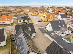 Ein Wohngebiet mit Häusern, einer asphaltierten Straße und einer entfernten Aussicht auf Dünen.