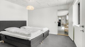 Una camera da letto moderna con un letto grande, una lampada a sospensione e vista sulla sala da pranzo.