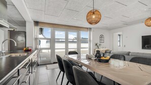 Una cucina moderna con un'isola grande, un'area pranzo con tavolo e sedie, e un divano grigio.