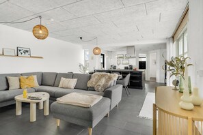 Ein modernes Wohnzimmer mit grauem Sofa, rundem Couchtisch und einem Holznachttisch.