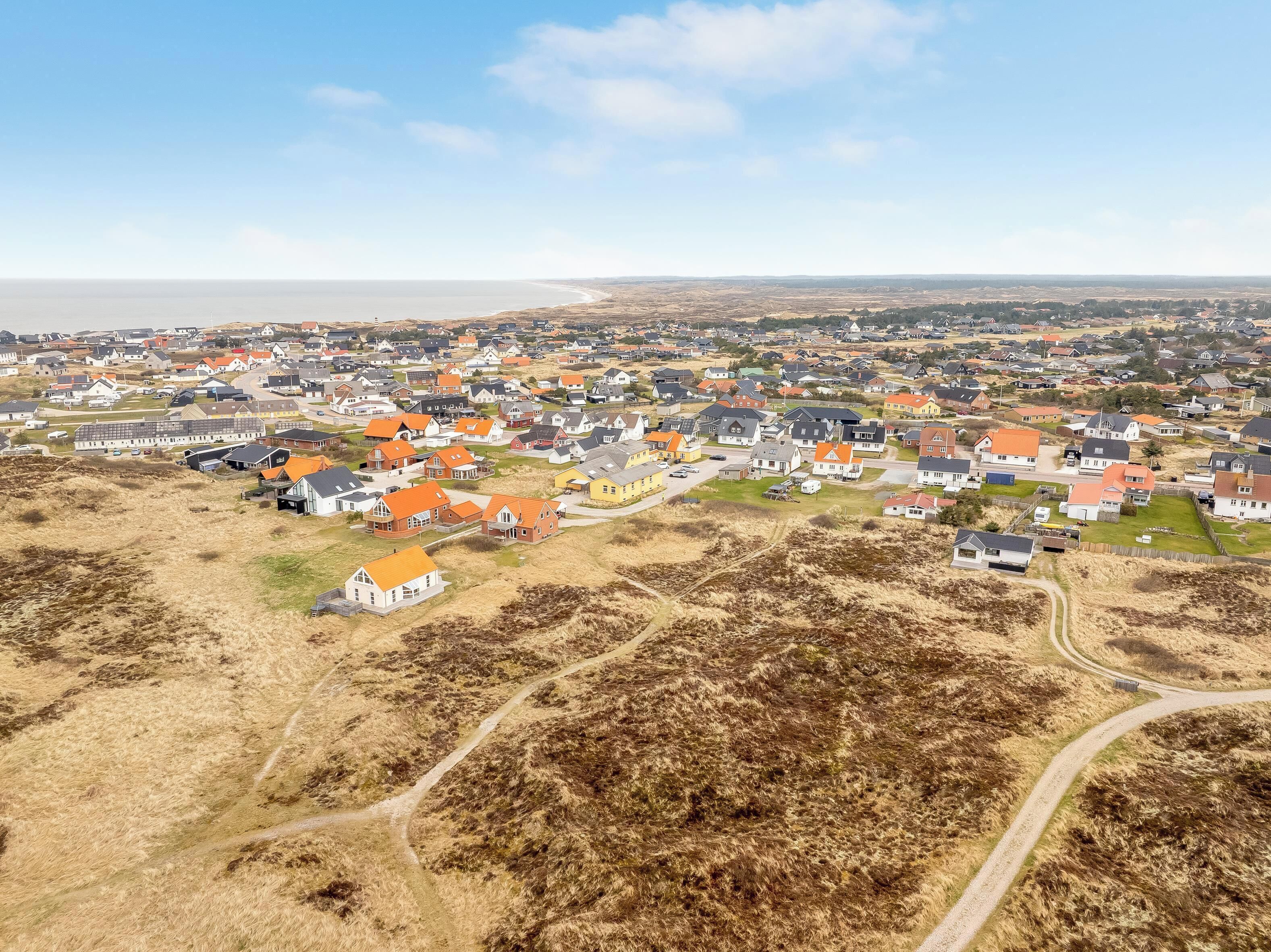 Vista aérea de una zona residencial con casas, calles y una playa a lo lejos.
