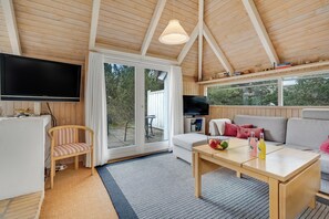 A cozy room with a television, a sofa, a dining table, and a chair. - Family-friendly cottage with shared activities such as swimming pool, tennis. (Fjerritslev)
