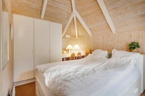 A bedroom with a wooden ceiling, a bed, a wardrobe, a desk with a lamp, and a chair. - Family-friendly cottage with shared activities such as swimming pool, tennis. (Fjerritslev)