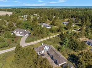 A residential area with houses surrounded by dense forests and a clear view of the ocean. - Family-friendly cottage with shared activities such as swimming pool, tennis. (Fjerritslev)