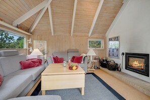 A cozy living room with a fireplace, a sofa, a coffee table, and a television. - Family-friendly cottage with shared activities such as swimming pool, tennis. (Fjerritslev)