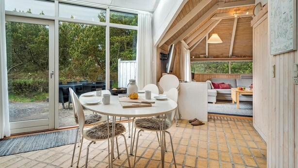 Um interior moderno com área de refeições, um sofá e teto de madeira.