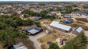 Vue aérienne d’un quartier résidentiel avec des maisons, un grand bâtiment doté d’un toit en métal et une piscine.
