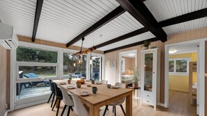Un espace repas avec une table en bois, des chaises et une vue dégagée grâce à de grandes fenêtres.
