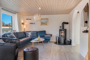 A modern living room with a sofa, coffee table, and a fireplace. - Cozy holiday home near the water with space for 5 people (Snedsted)