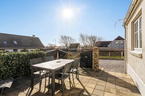 A patio with a table and chairs, a stone wall, and a view of neighboring houses.