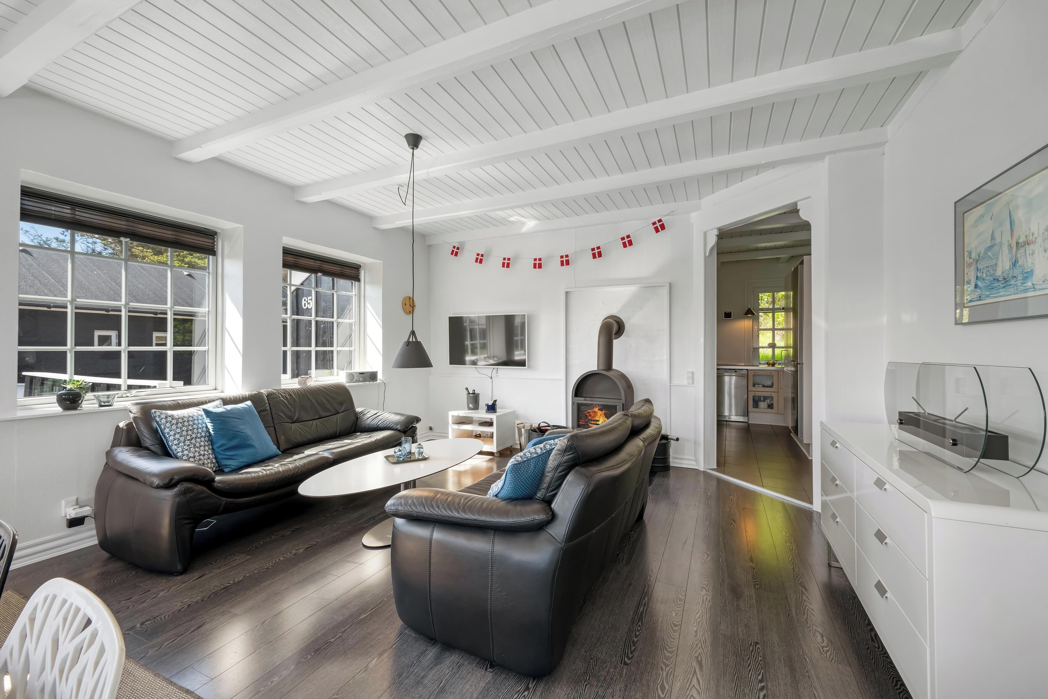 A modern living room with a fireplace, leather sofas, and a dining area.
