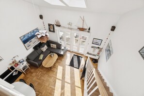 Ein geräumiges Wohnzimmer mit Sofa, Couchtisch und einer Treppe zu einer oberen Etage.