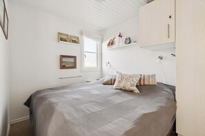 Ein Schlafzimmer mit einem Bett, einem Fenster, einer Ablage mit Dekoration und einem Kleiderschrank.