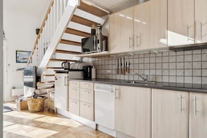 Eine moderne Küche mit Holzschränken, einer Mikrowelle und einem Spülbecken.