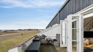 Une terrasse extérieure couverte, équipée d’un barbecue, de sièges et offrant une vue sur le paysage.