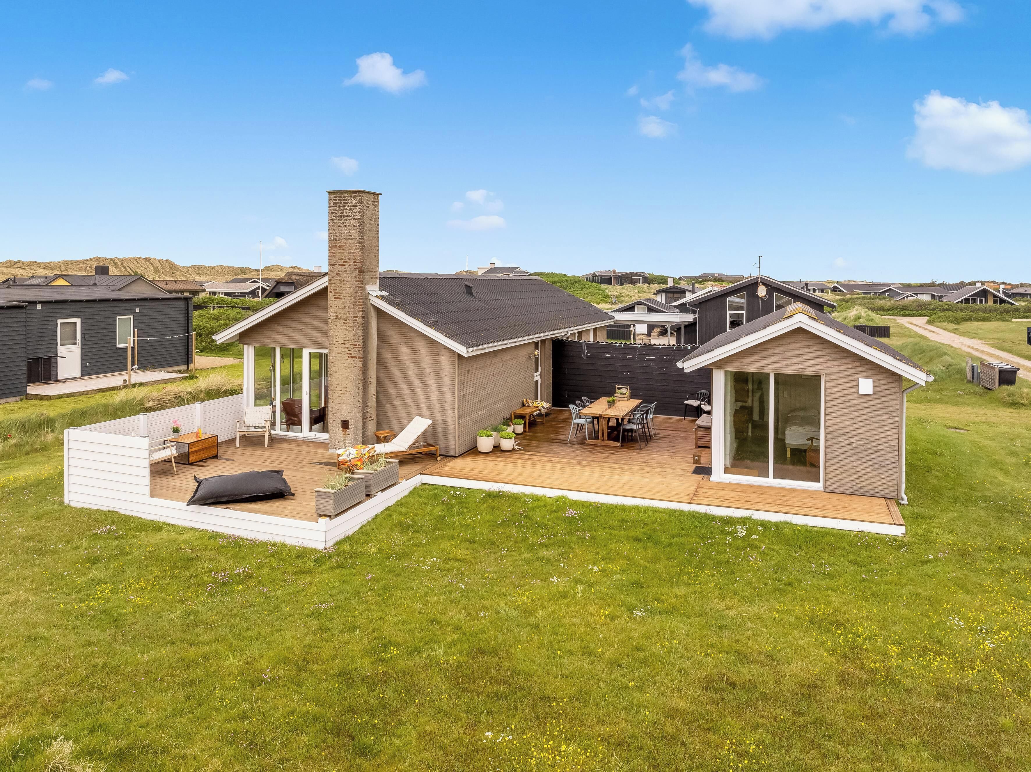 Een modern huis met een terras, een patio en een klein bijgebouw.