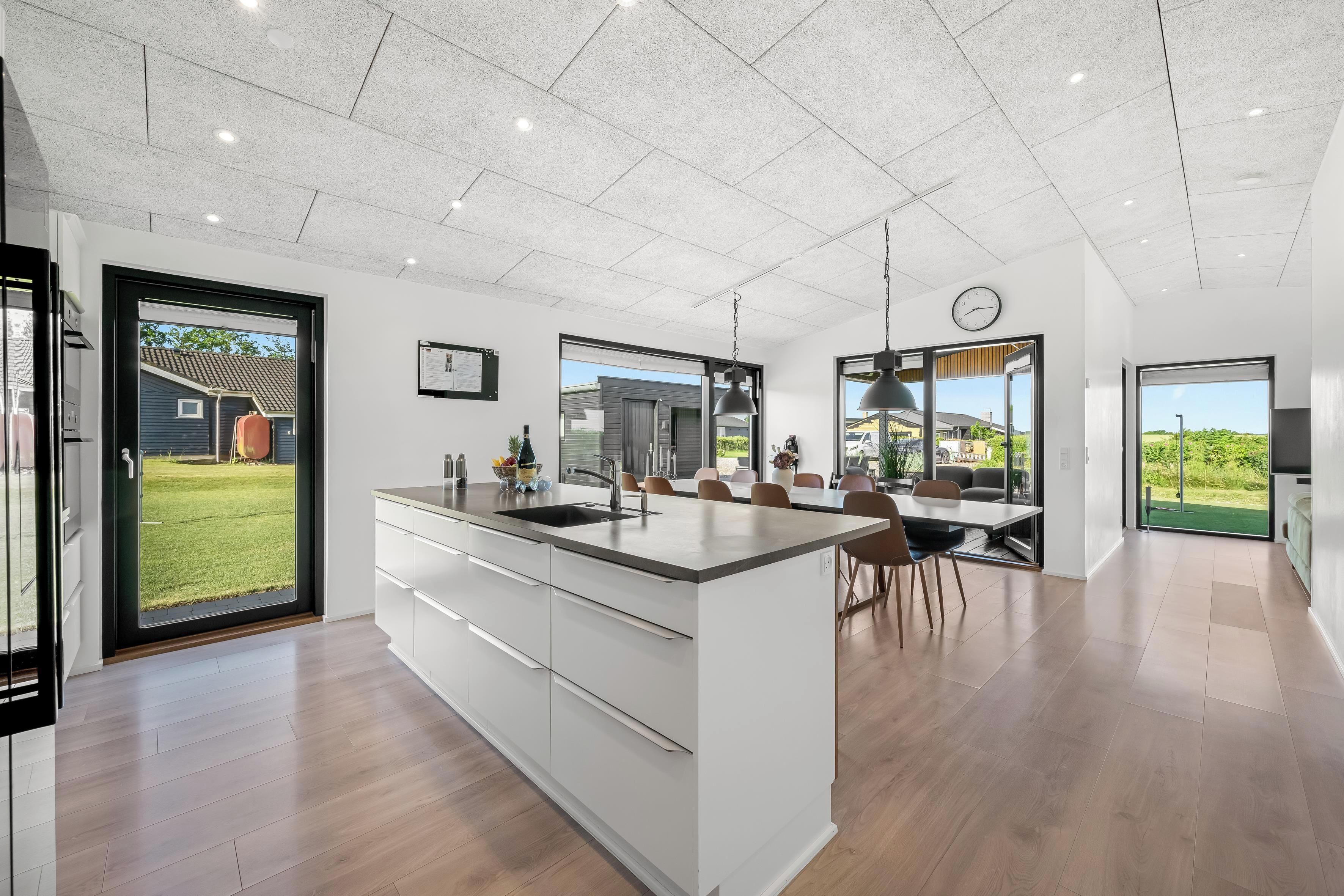A modern kitchen with a large island, a dining area with chairs, and a view of the outdoors.