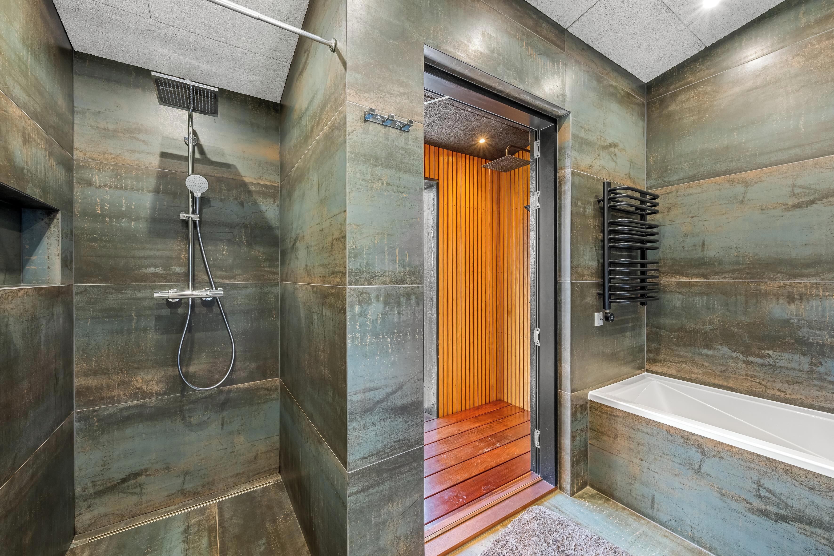 Une salle de bain moderne équipée d’une douche, d’une baignoire et d’une porte en bois donnant sur une autre pièce.