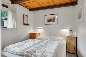Ein Schlafzimmer mit zwei Betten, einem Holzschrank, einem Spiegel und einem gerahmten Bild an der Wand.