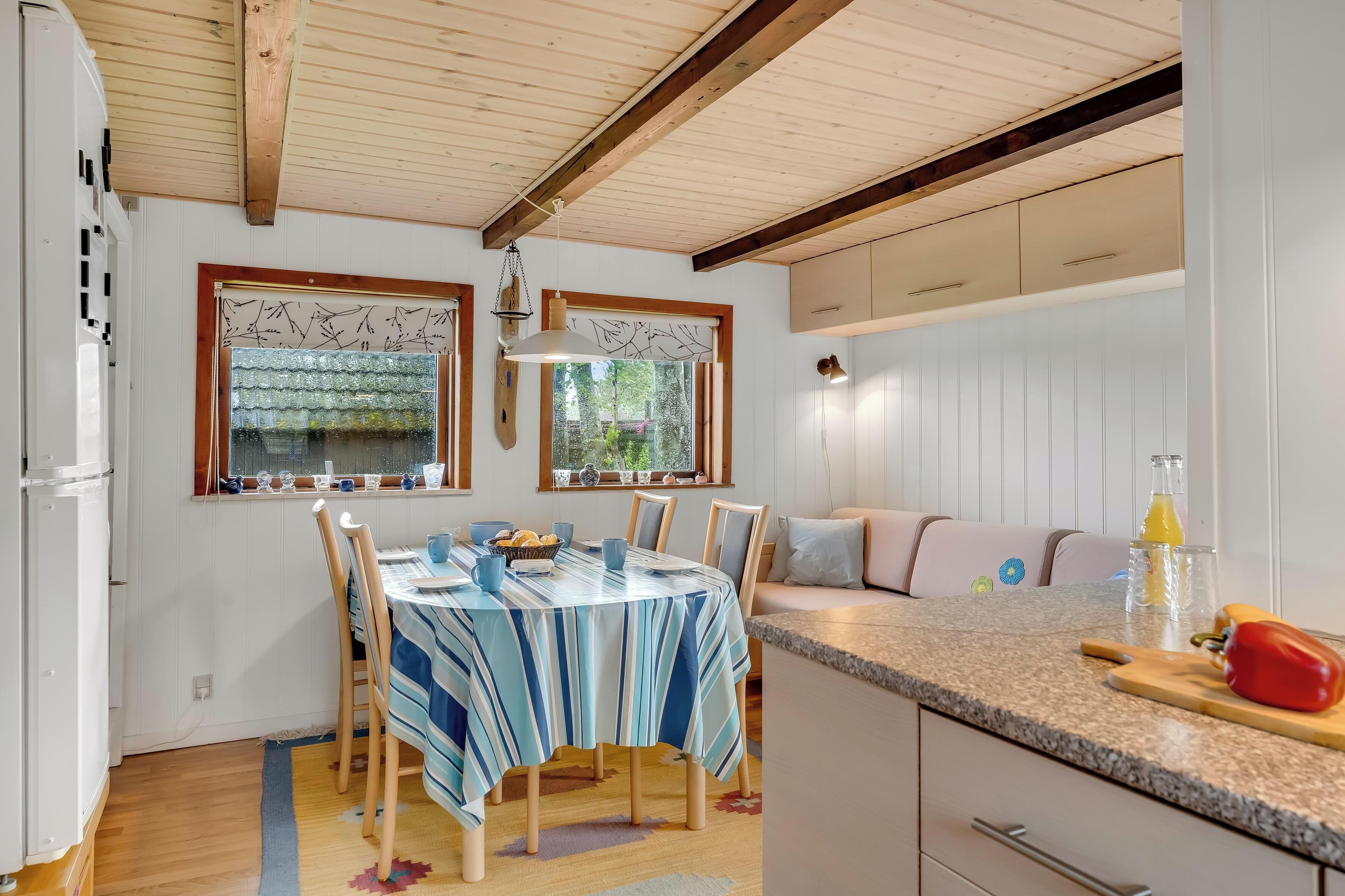 Une cuisine équipée d’une table à manger, de chaises, d’un plan de travail et d’une fenêtre donnant sur un beau paysage.
