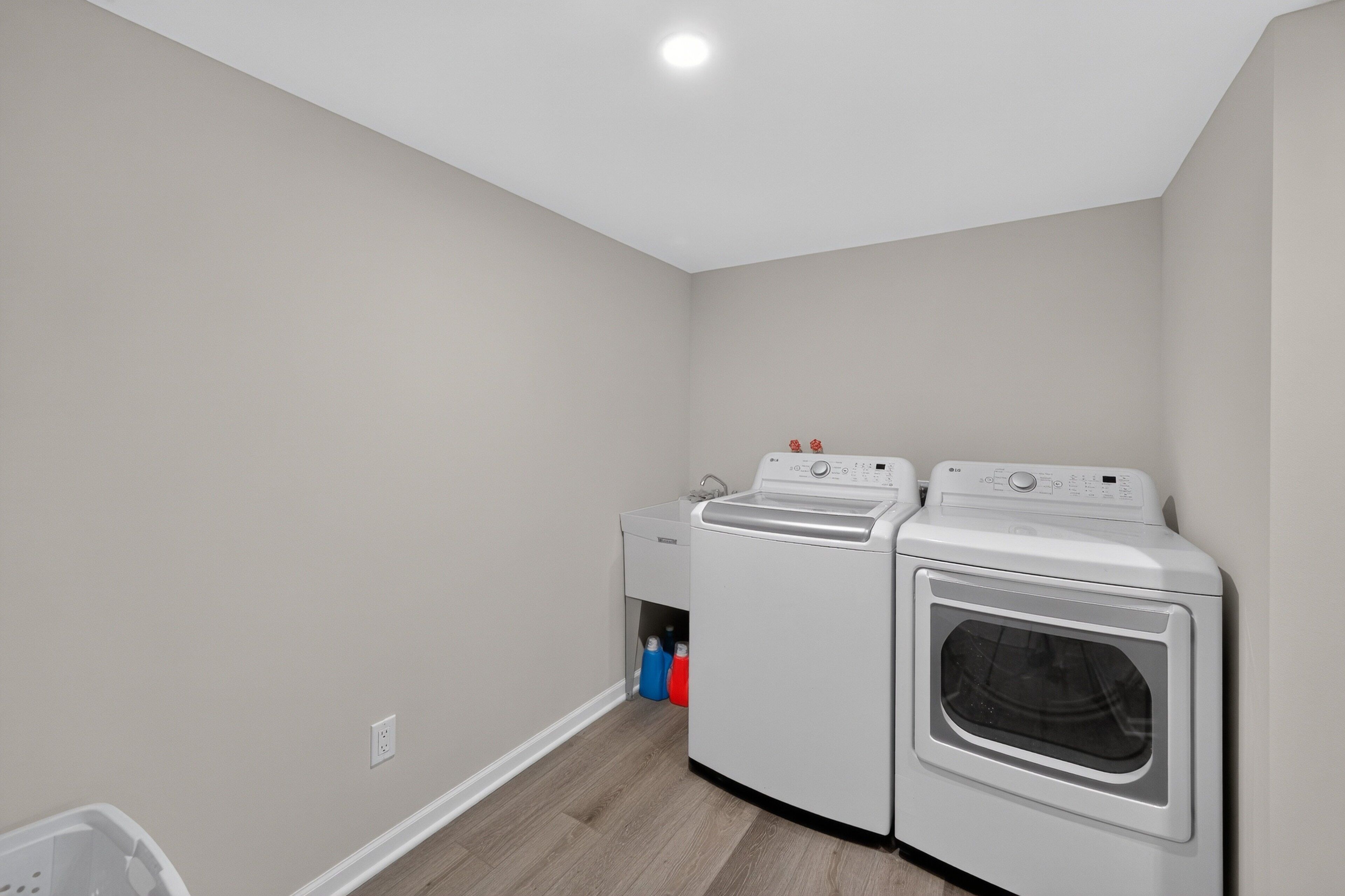 A laundry room with a washing machine, dryer, and a utility sink.