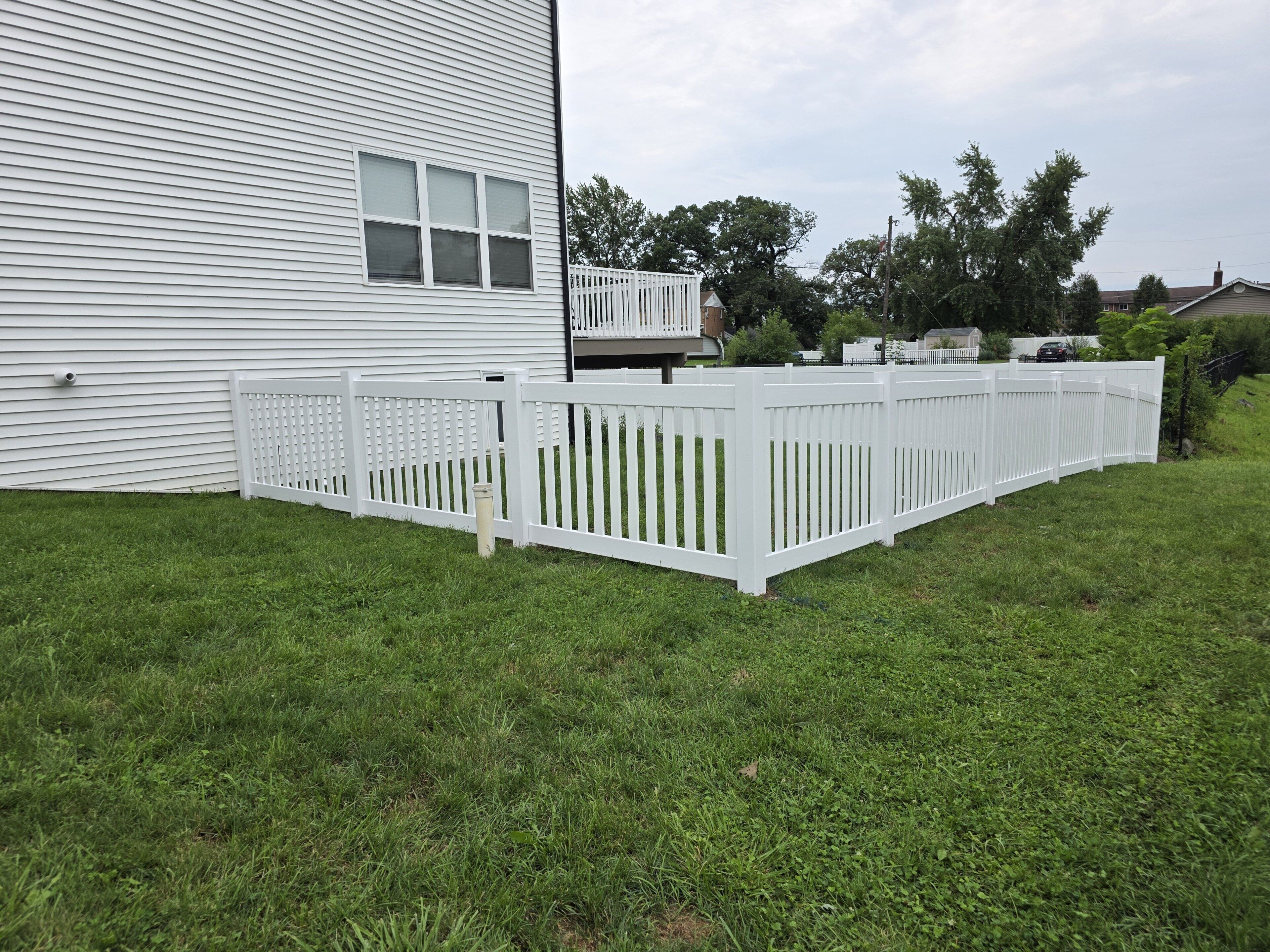 A white house with a fenced backyard.