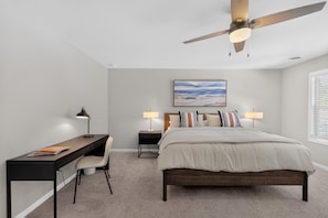 A bedroom with a bed, desk, chair, two bedside tables with lamps, a ceiling fan, and a painting on the wall. - Cedar Lake 4br Home For 8 W/ Lake Views 4 Bedroom Home (Cedar Lake)