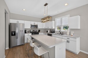 A modern kitchen with stainless steel appliances, a central island with bar stools, and a pendant light. - Cedar Lake 4br Home For 8 W/ Lake Views 4 Bedroom Home (Cedar Lake)
