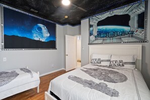Ein Schlafzimmer mit einem Bett, das mit Star Wars-Betwäsche, einem Wandgemälde einer Raumstation und einem Blick auf die Erde aus einem Raumschiff-Fenster ausgestattet ist.