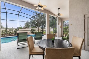 Überdachte Terrasse mit Pool, Außenmöbeln und Deckenventilatoren.