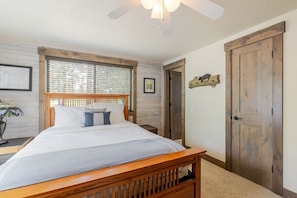 A bedroom with a wooden bed, a ceiling fan, a window with blinds, and a wooden door. - 14 Lark Lane 4 Bedroom Home (Bend)