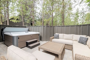 An outdoor patio with a hot tub, a sofa, and wicker furniture. - 14 Lark Lane 4 Bedroom Home (Bend)