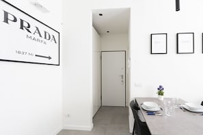 Ein modernes Interieur mit einem für vier Personen gedeckten Esstisch, einer weißen Tür und gerahmten Bildern an der Wand.