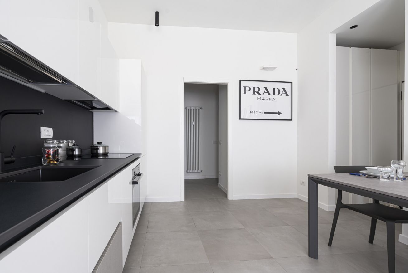 A modern kitchen with a black countertop, white cabinets, and a dining area with a table and chairs.