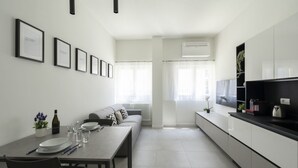 A modern kitchen with a dining area, white cabinetry, and a built-in TV. - GuestHost - Comfy TERRA Apartment near Cenisio MM5 (Milan)