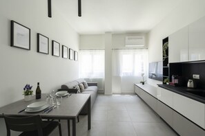 A modern kitchen with a dining area, white cabinetry, and a built-in TV. - GuestHost - Comfy TERRA Apartment near Cenisio MM5 (Milan)