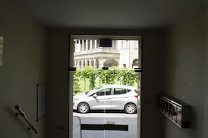 Eine Tür, die zu einer Straße führt, vor der ein weißes Auto geparkt ist.
