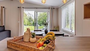 A dining area with a wicker fruit basket, a vase, and a table set for two. - Saron 2.0 Spa (Denbigh)