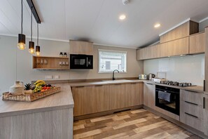 Eine moderne Küche mit Holzschränken, einer eingebauten Mikrowelle, einem Gasherd und einer Obstschale auf der Arbeitsfläche.