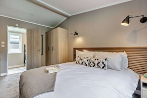 A bedroom with a bed, bedside tables, a wardrobe, and a ceiling light fixture. - Saron 2.0 Spa (Denbigh)
