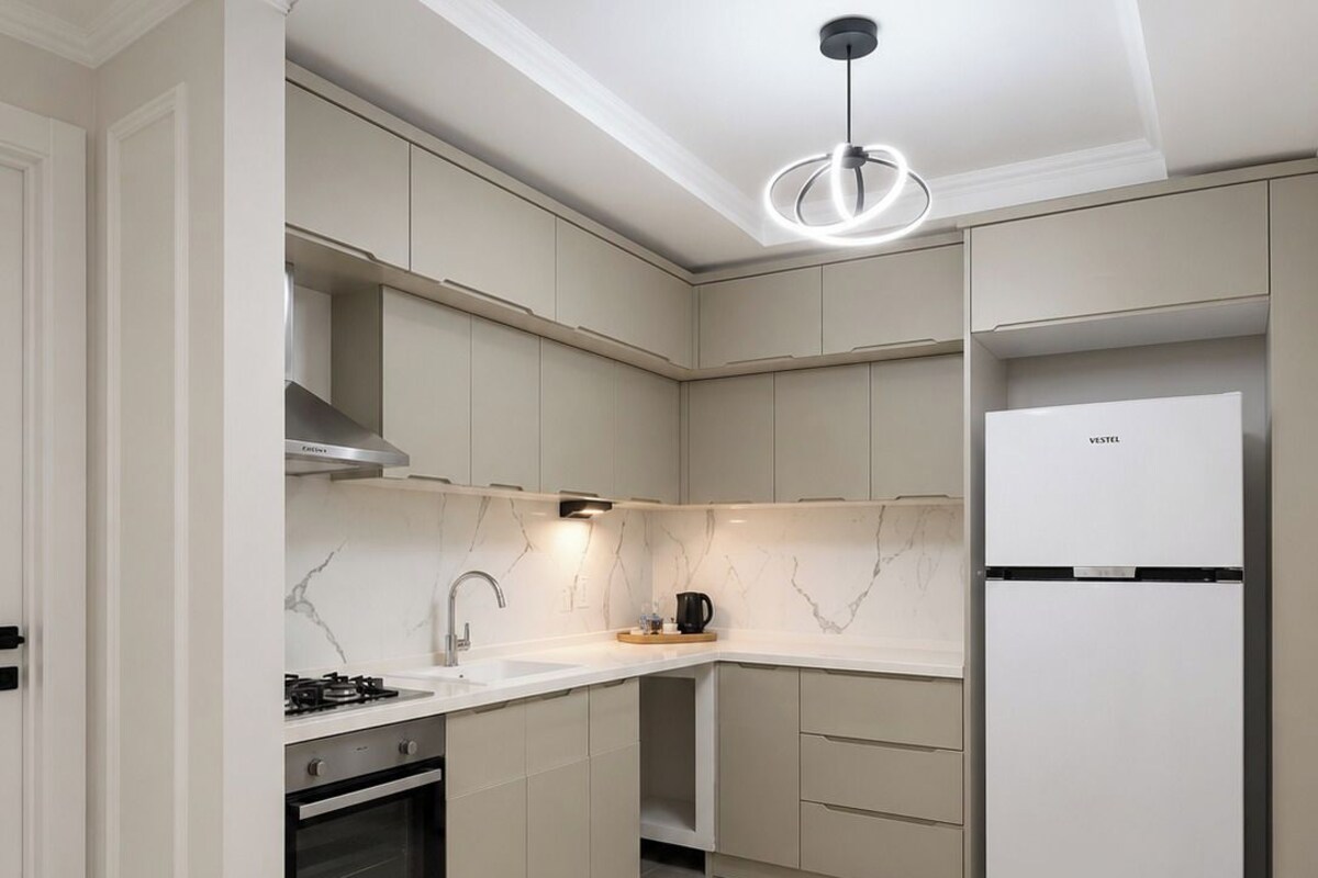A modern kitchen with a built-in oven, a coffee maker, and a white refrigerator.