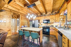 Ein Holzblockhaus-Innenraum mit Küche, Bar und Sitzgelegenheiten.