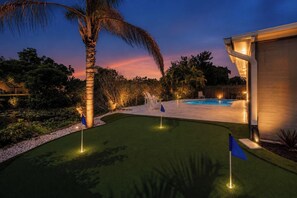 Ein Garten mit Schwimmbad, Kunstrasen und einer Palme.