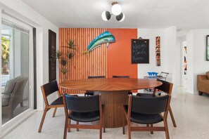 Ein zeitgemäßer Essbereich mit einem runden Holztisch, umgeben von Stühlen, einem dekorativen Fisch an der Wand und einem Kreidetafel-Schild.