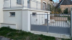 Een gebouw met twee verdiepingen, een balkon, een hekwerk en een klein raam.