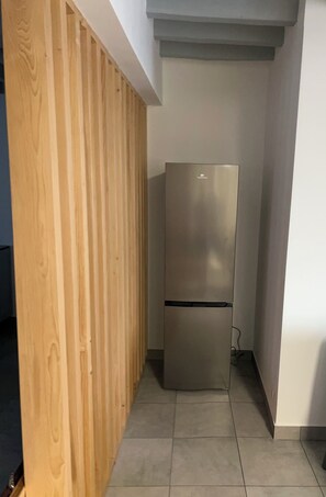 A corner of a room with a wooden partition and a stainless steel refrigerator. - A lovely, spacious, quiet house with a charming little yard (Dampierre-sous-Bouhy)