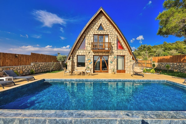 A stone house with a swimming pool, a balcony, and a wooden fence. - Serene Bungalow Retreat With Private Pool in Kaş, Türkiye (Kaş)